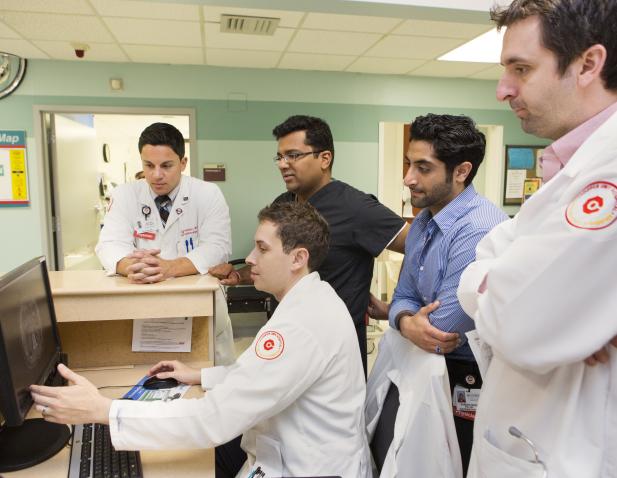 Faculty and attendings surround a computer monitor